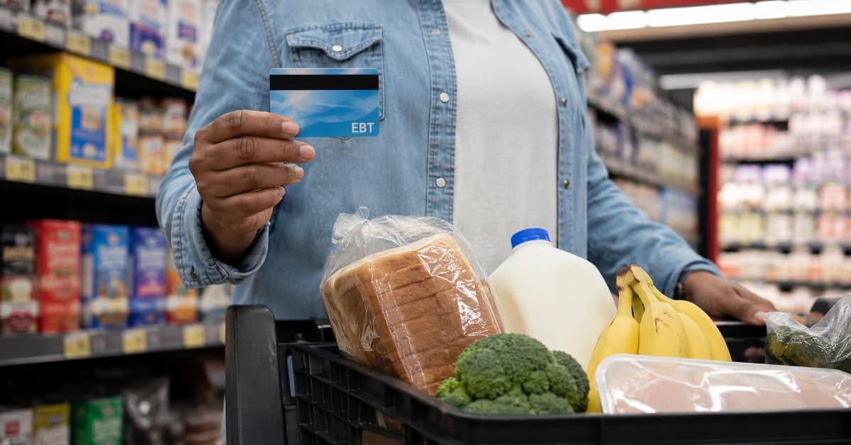 Persona sostiene una tarjeta EBT mientras realiza la compra de alimentos en un supermercado de Estados Unidos.