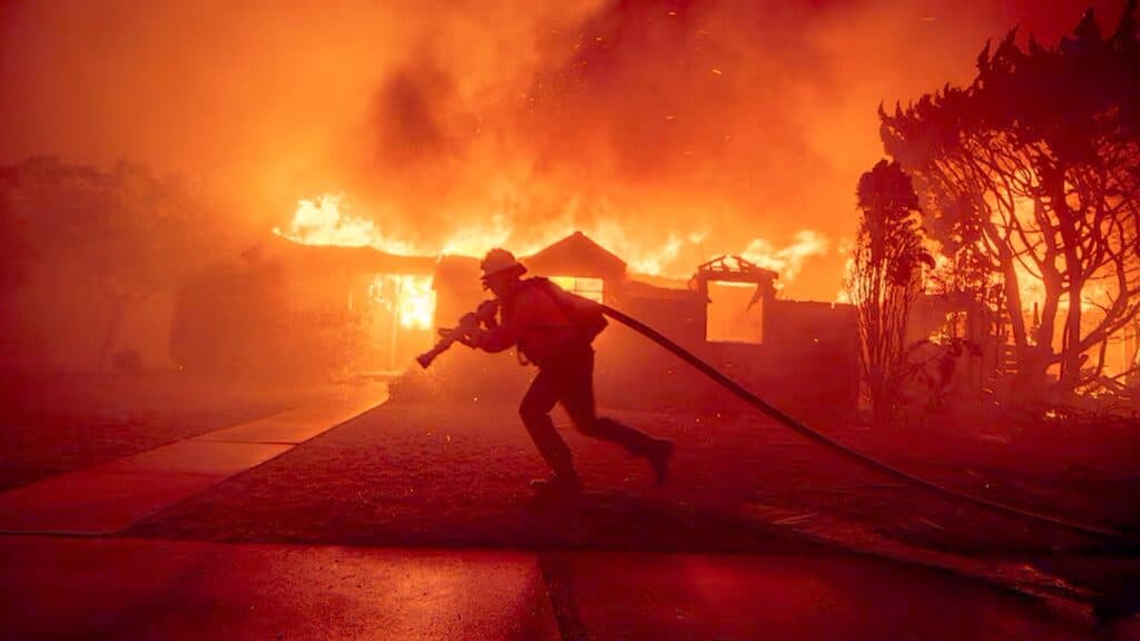 Bombero Cargando Manguera Frente a Vivienda Incendiada