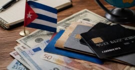 Persona revisa documentos financieros y una laptop como referencia a cuentas bancarias en divisas fuera de Cuba