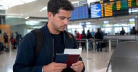 Viajero cubano con doble ciudadanía sostiene dos pasaportes en un aeropuerto antes de viajar a Cuba.