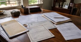 Documentos legales, certificados y título de propiedad sobre una mesa durante un trámite de herencia en Cuba.
