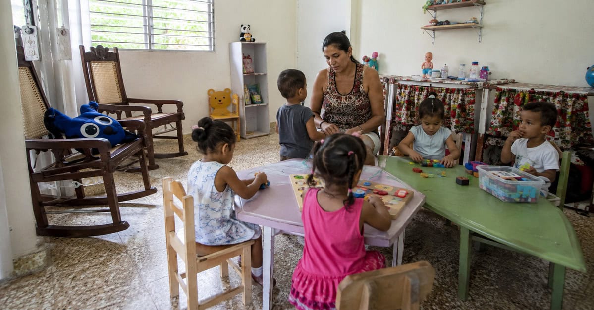 Espacio privado de cuidado infantil en Cuba donde una cuidadora supervisa a varios niños pequeños mientras realizan actividades educativas en un ambiente seguro y organizado.