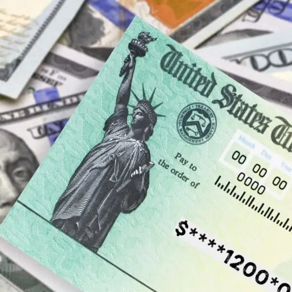 Cheques Ayuda de Estados Unidos junto a varios billetes de cien dolares americanos