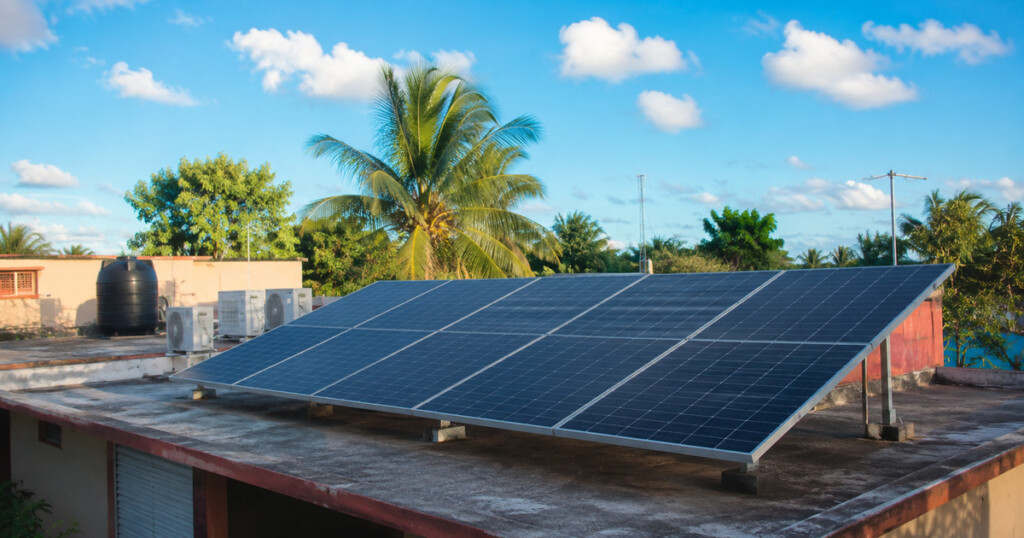 Sistema de paneles solares modernos instalado en el techo de una vivienda típica de Cuba durante una tarde soleada.