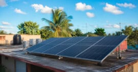 Sistema de paneles solares modernos instalado en el techo de una vivienda típica de Cuba durante una tarde soleada.