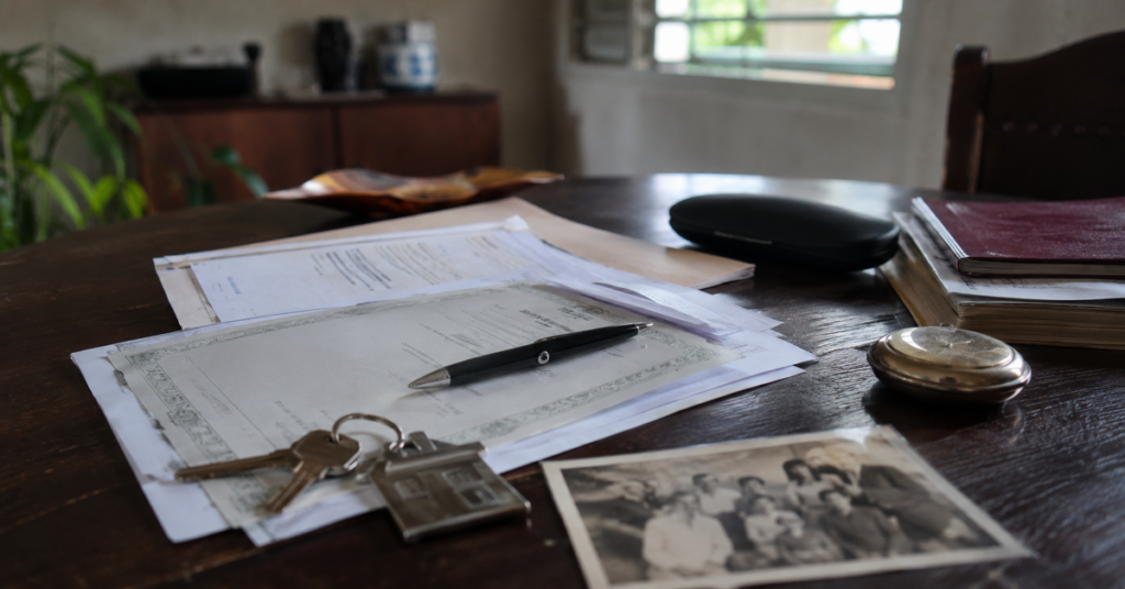 Documentos legales, llaves de una vivienda y objetos personales sobre una mesa durante un procedimiento de herencia en Cuba.