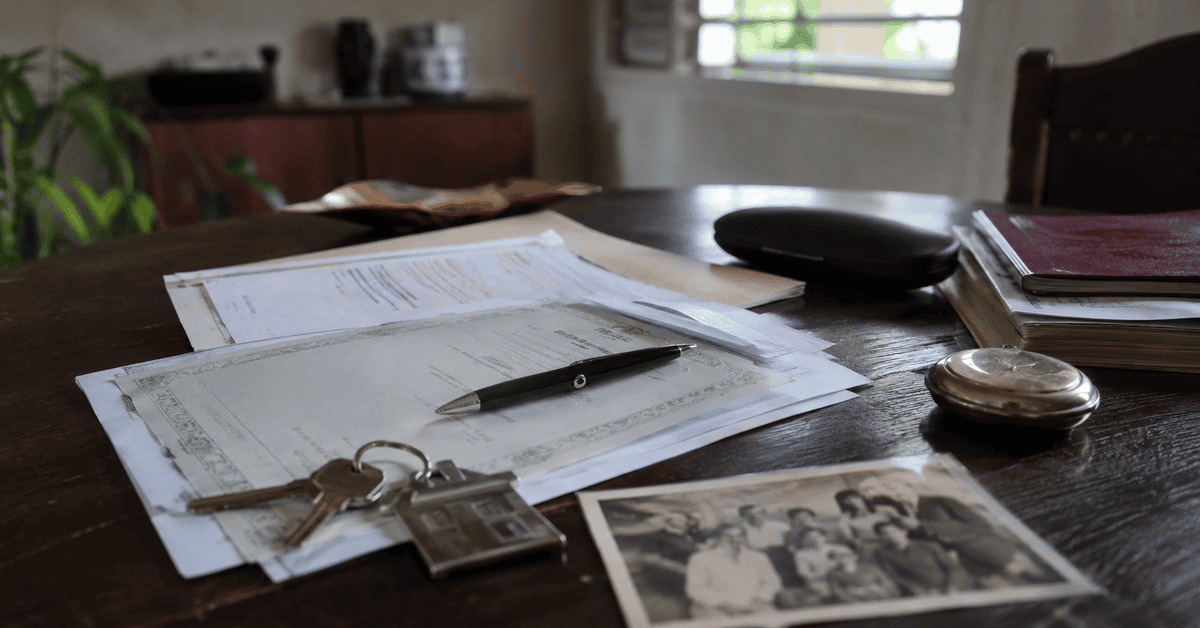 Documentos legales, llaves de una vivienda y objetos personales sobre una mesa durante un procedimiento de herencia en Cuba.