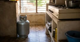 Cilindro doméstico de gas licuado de 10 kilogramos junto a una cocina en una vivienda cubana