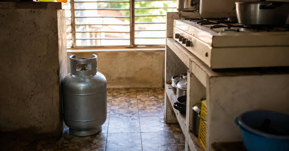 Cilindro doméstico de gas licuado de 10 kilogramos junto a una cocina en una vivienda cubana