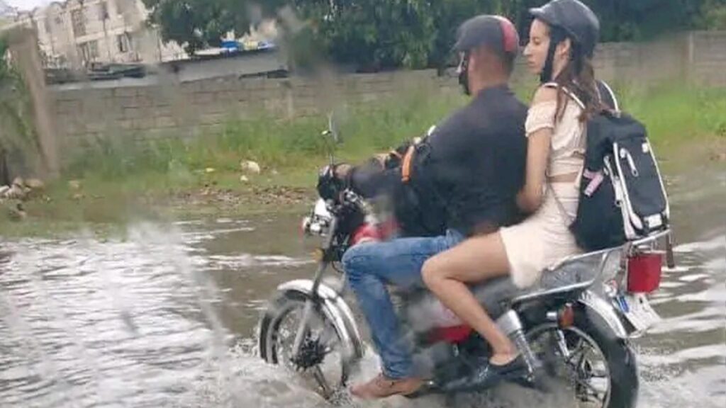 Personas en Moto Transitando por Calle Inundada