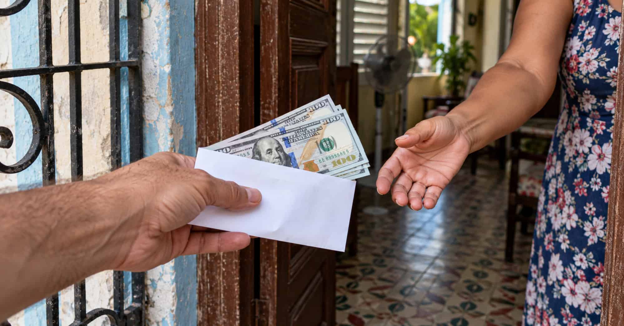 Una mano entrega un sobre con dólares a una mujer en el umbral de una vivienda cubana.