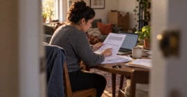 Persona latina revisando documentos de alquiler y comprobantes de ingresos en un apartamento de Estados Unidos