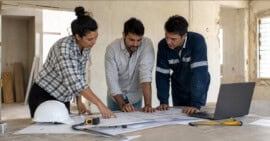 Arquitectos e ingeniero revisando planos de construcción en una vivienda en proceso de remodelación en Cuba.