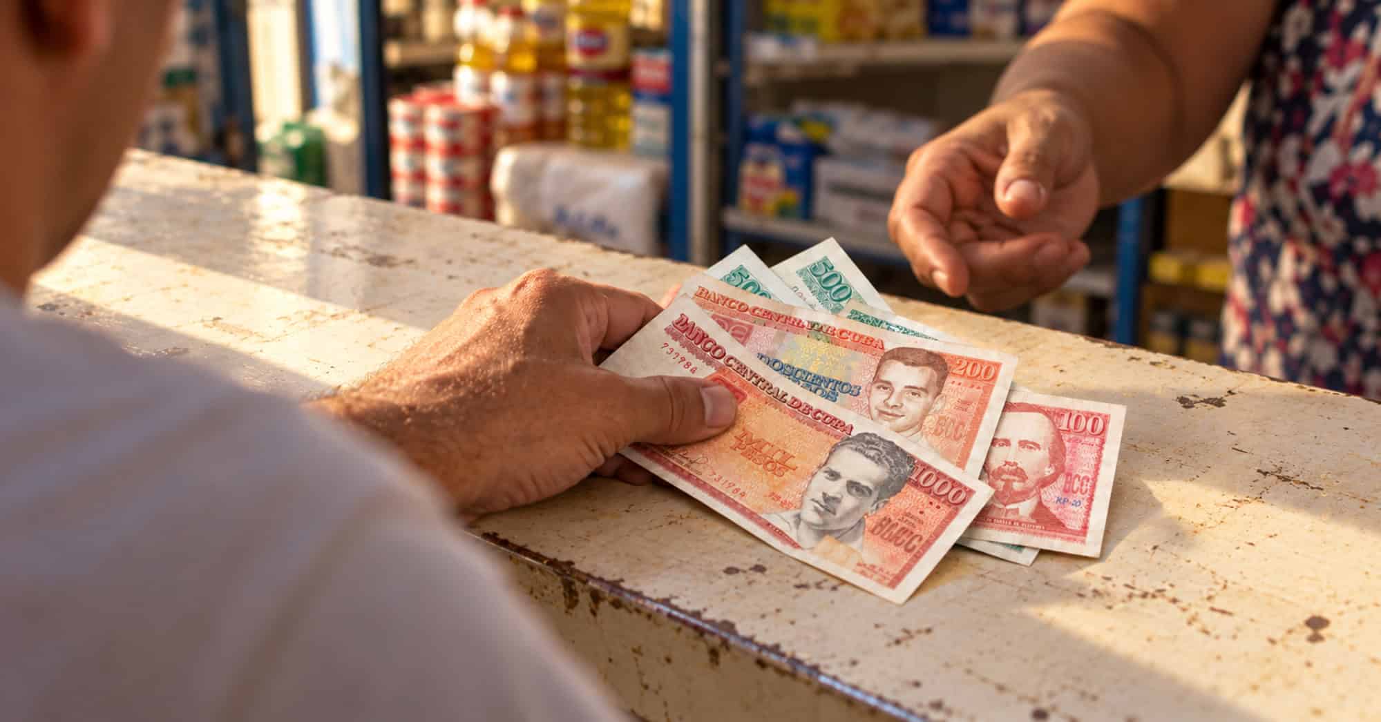 Una persona coloca billetes de pesos cubanos sobre el mostrador de un comercio.