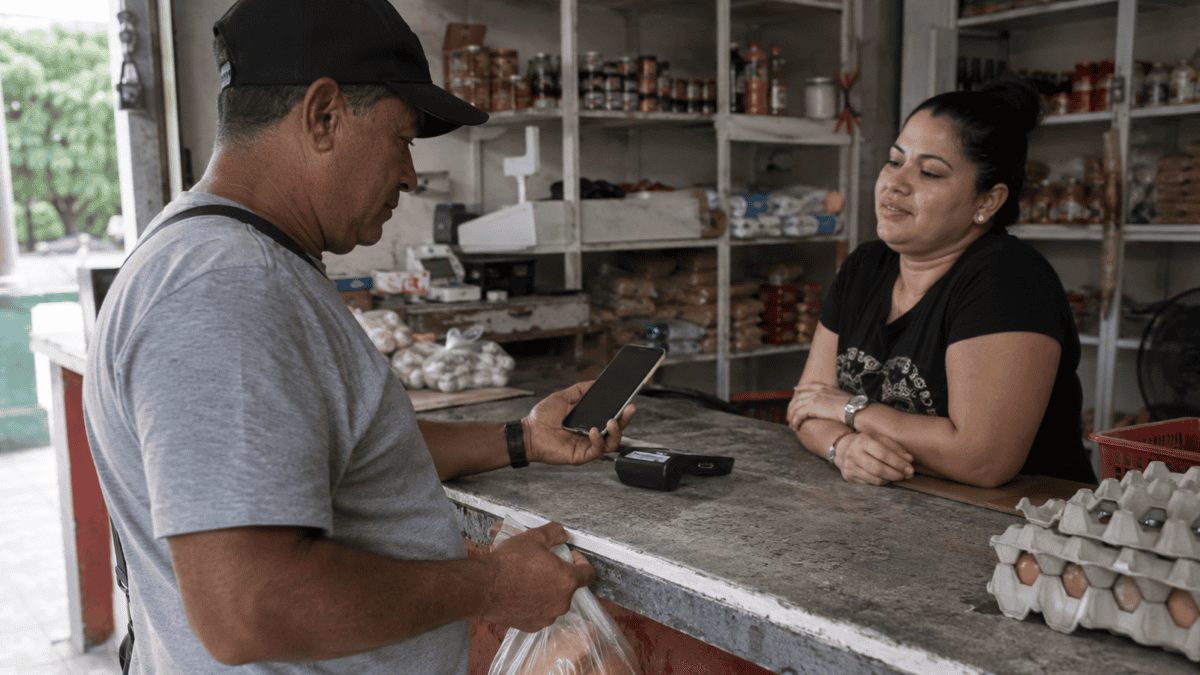Persona realiza un pago electrónico con su teléfono móvil en un comercio cotidiano en Cuba.