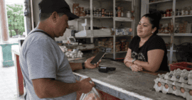 Persona realiza un pago electrónico con su teléfono móvil en un comercio cotidiano en Cuba.