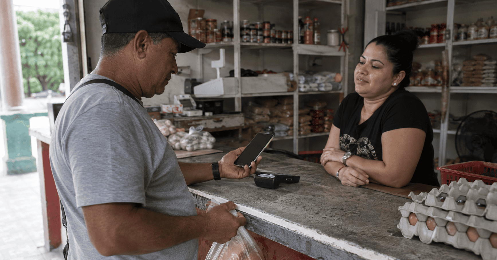 Persona realiza un pago electrónico con su teléfono móvil en un comercio cotidiano en Cuba.