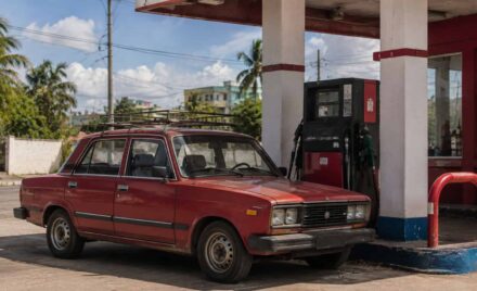 Automóvil antiguo junto a un surtidor de combustible en una estación de servicio cubana