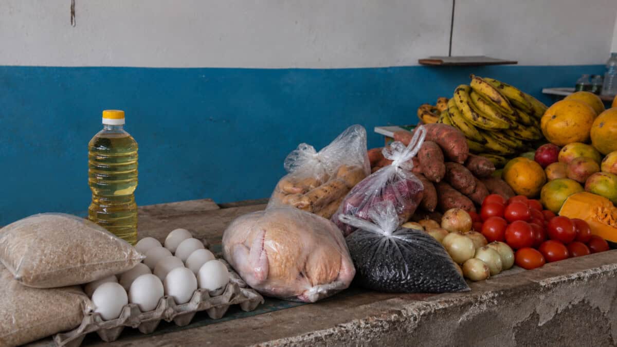 Mostrador de un mercado cubano con arroz, huevos, aceite, pollo, frijoles, viandas, tomates, cebollas y frutas.