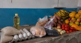 Mostrador de un mercado cubano con arroz, huevos, aceite, pollo, frijoles, viandas, tomates, cebollas y frutas.