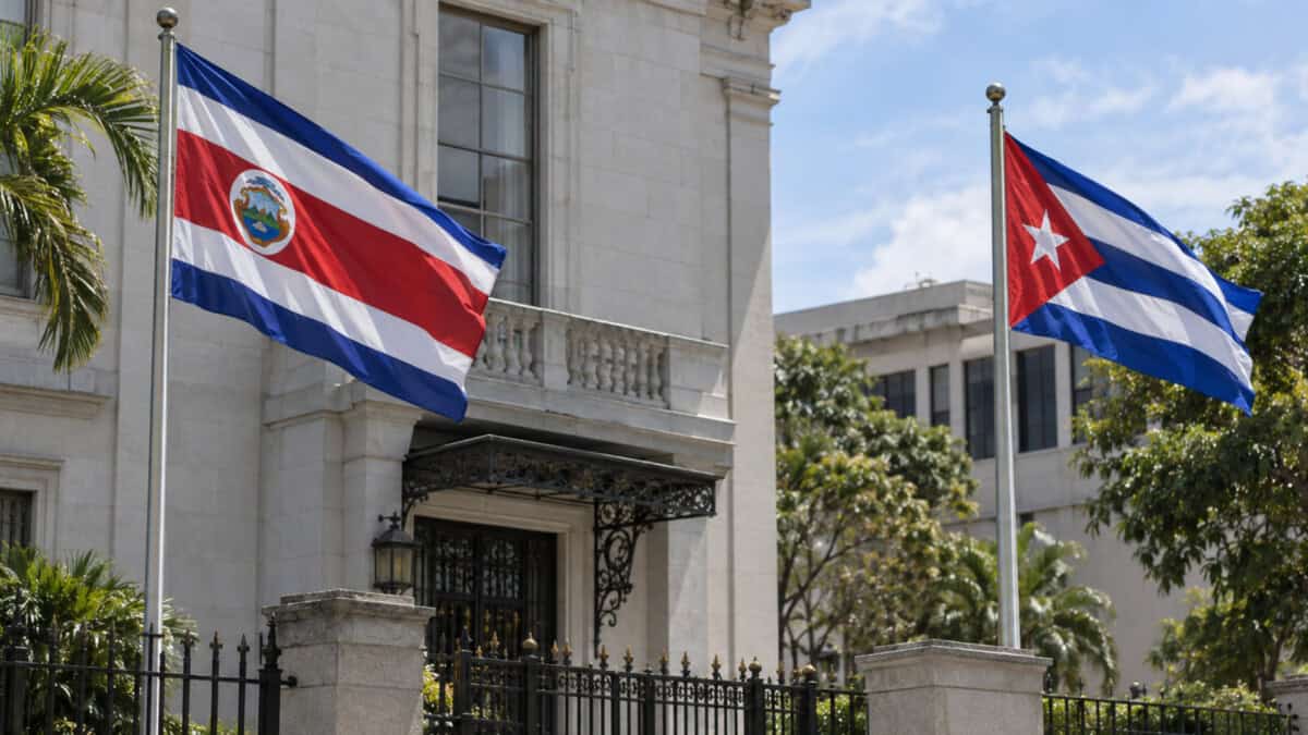 Banderas de Costa Rica y Cuba ondean en astas separadas frente a un edificio institucional.