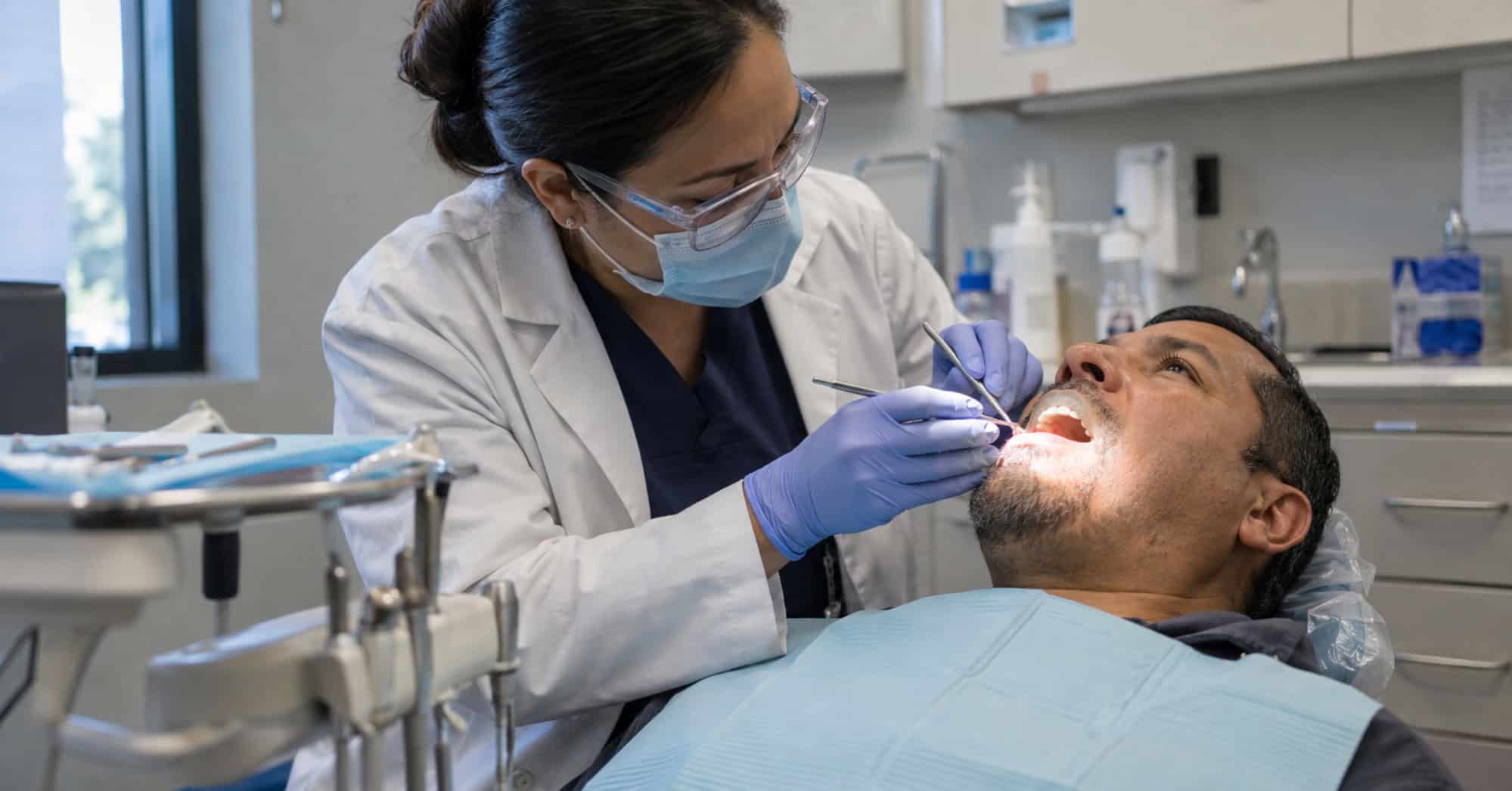 Dentista examina a un paciente adulto durante una consulta en una clínica comunitaria de Estados Unidos.