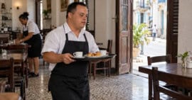 Persona adulta con síndrome de Down sirve café y bocaditos como dependiente en un local gastronómico cubano.