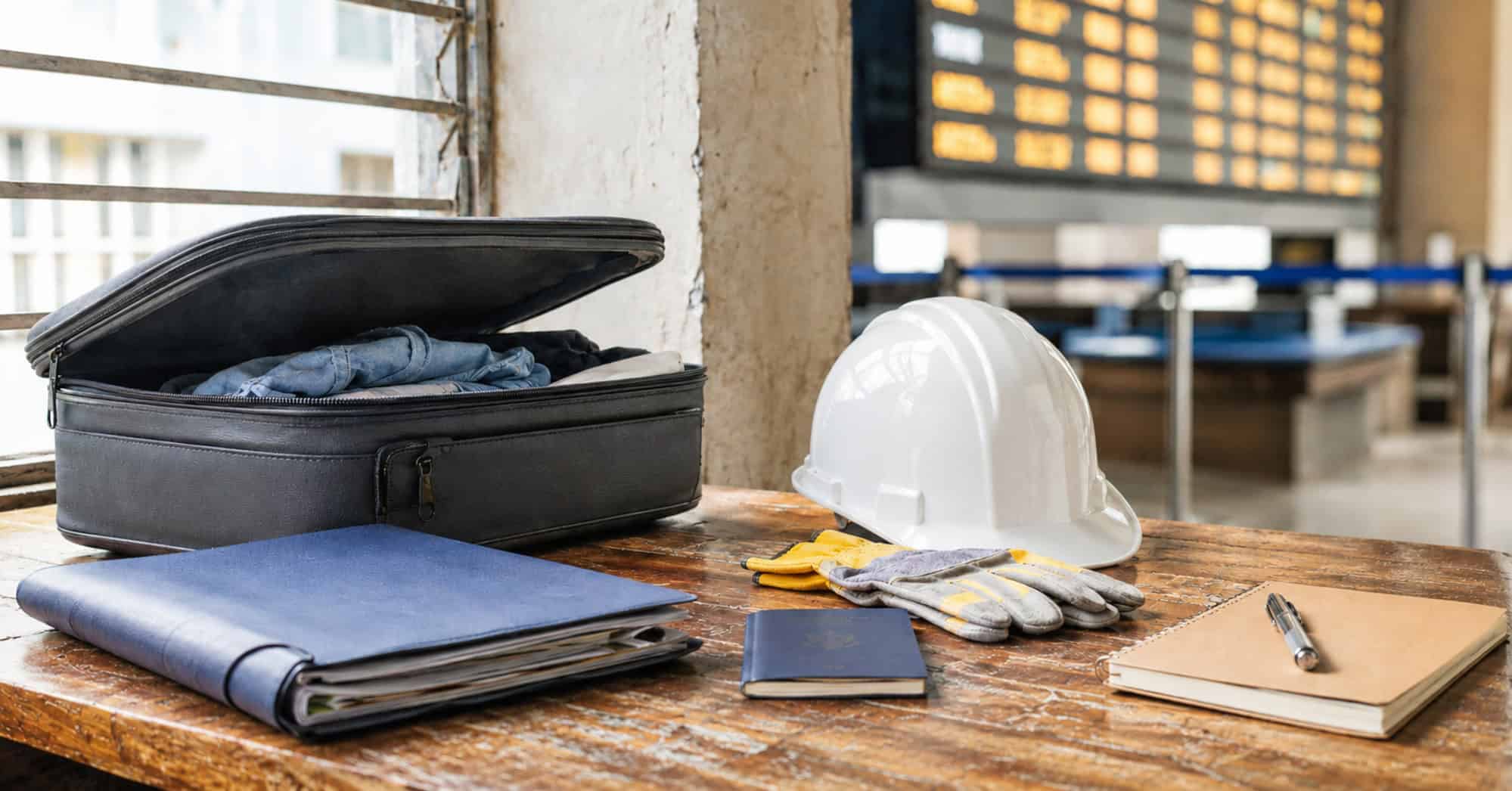 Maleta, pasaporte y herramientas de trabajo que representan la búsqueda de empleo legal en el extranjero para cubanos.