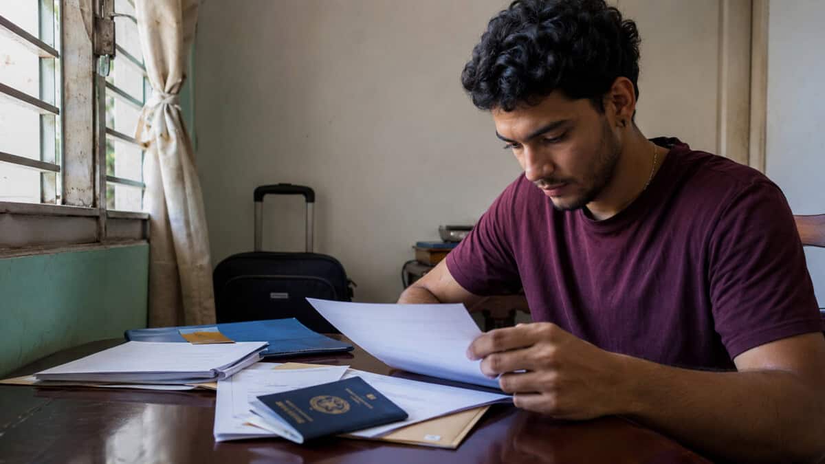Joven adulto cubano revisa documentos académicos y su pasaporte para solicitar estudios en el extranjero.