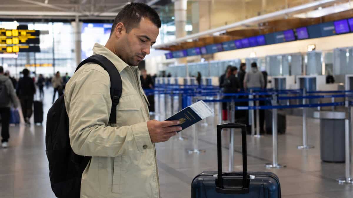 Persona cubana con pasaporte y equipaje en un aeropuerto internacional antes de emigrar por motivos laborales.
