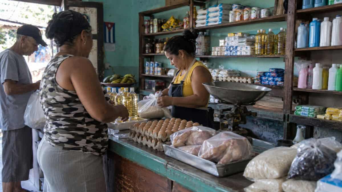 Clientes compran alimentos y productos de aseo en un pequeño mercado de barrio en Cuba.