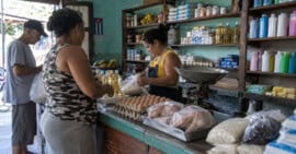 Clientes compran alimentos y productos de aseo en un pequeño mercado de barrio en Cuba.