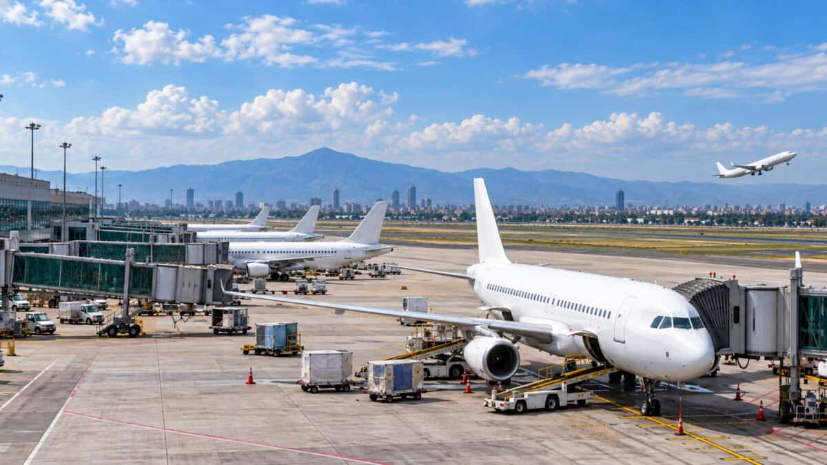 Aviones comerciales estacionados junto a una terminal aeroportuaria en México y una aeronave despegando al fondo.