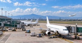 Aviones comerciales estacionados junto a una terminal aeroportuaria en México y una aeronave despegando al fondo.
