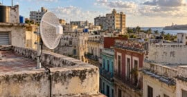 Antena inalámbrica tipo MikroTik instalada en una azotea, con edificios residenciales cubanos al fondo.