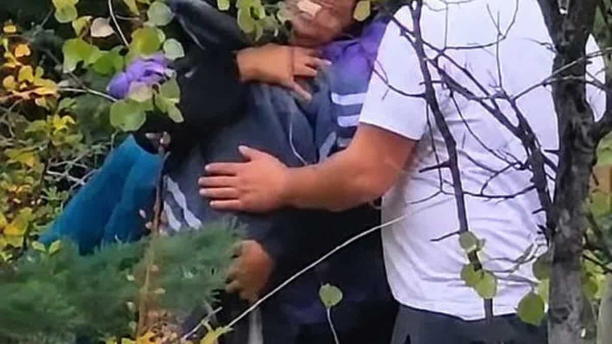 Varias personas entre vegetación, una de ellas sosteniendo a otra en brazos.