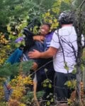 Varias personas entre vegetación, una de ellas sosteniendo a otra en brazos.