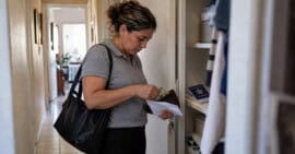 Mujer guarda dólares en un sobre en su vivienda, junto a un pasaporte cubano y una carpeta.