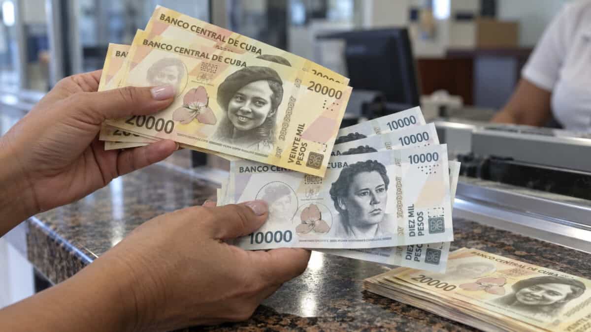 Persona cuenta nuevos billetes cubanos de 10 000 y 20 000 CUP en una sucursal bancaria.