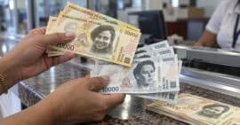 Persona cuenta nuevos billetes cubanos de 10 000 y 20 000 CUP en una sucursal bancaria.