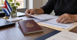 Persona organiza documentos consulares junto a un pasaporte cubano para realizar un trámite desde el exterior.