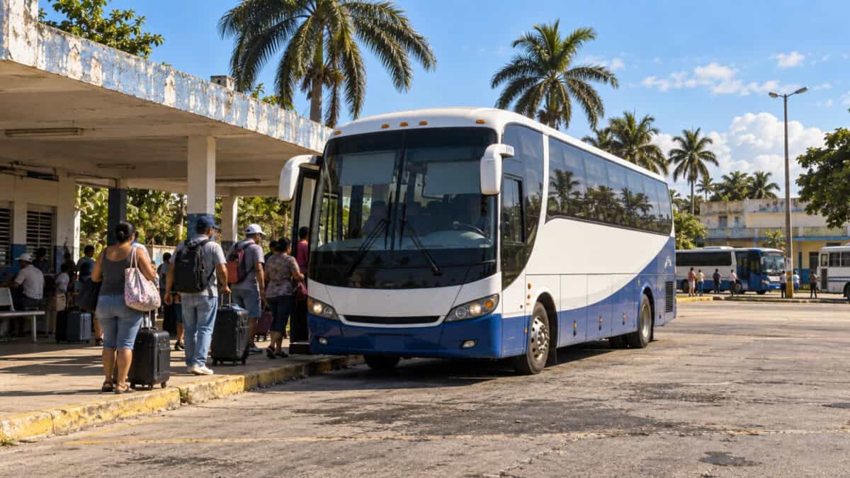 Ómnibus moderno estacionado en un parqueo de transporte interprovincial en Cuba, con viajeros y equipajes.