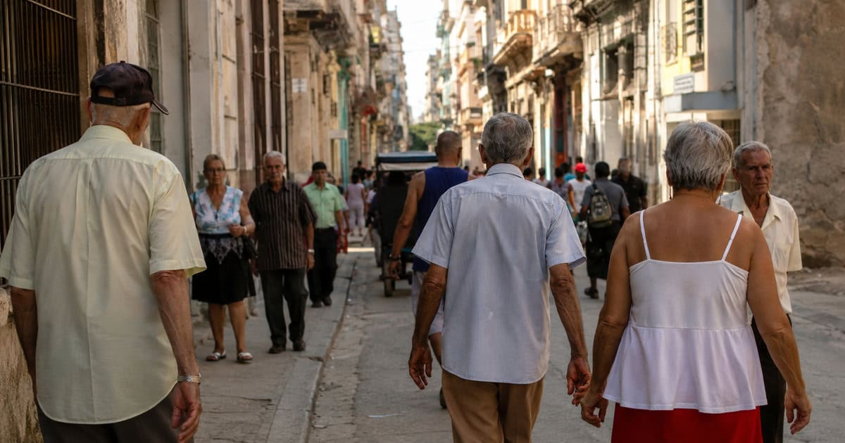 Vista de una calle en Cuba con personas mayores y pocos jóvenes, ilustrando el envejecimiento demográfico de la población cubana.