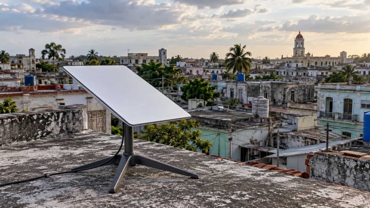 Antena de internet satelital Starlink sobre una azotea de hormigón, con viviendas cubanas al fondo.