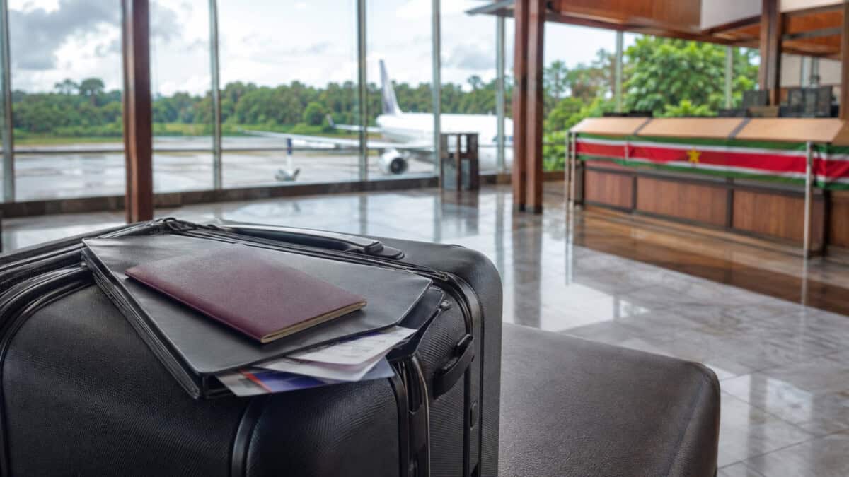 Maleta y documentos de viaje en una terminal aérea de Surinam