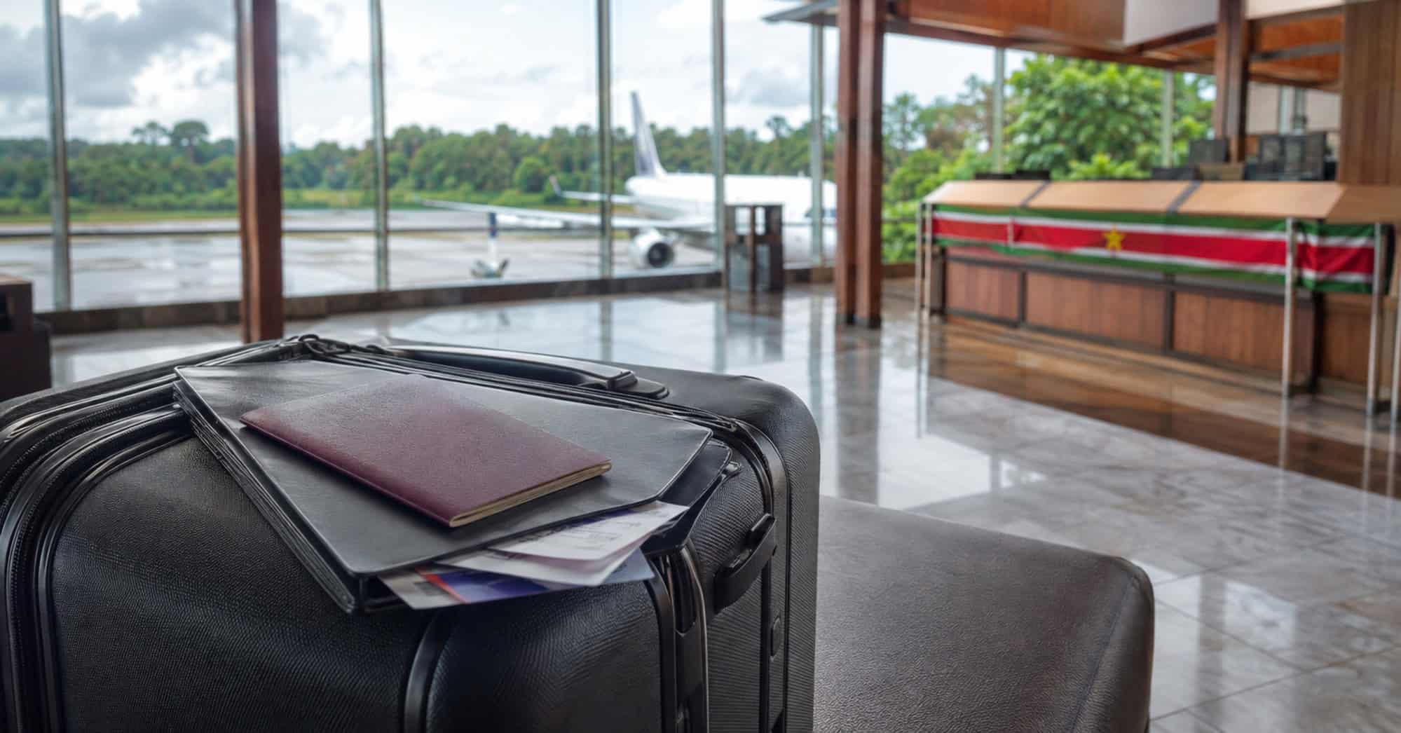Maleta y documentos de viaje en una terminal aérea de Surinam