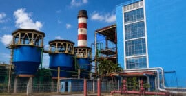Vista panorámica de una central termoeléctrica en Cuba con tanques industriales, chimenea y edificio de generación eléctrica.