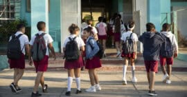 Grupo de estudiantes cubanos con uniforme y ropa particular llegando a una escuela pública al inicio del curso escolar.