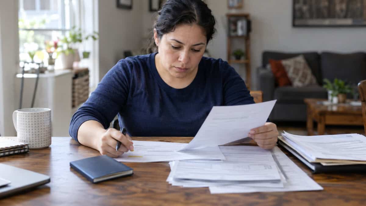 Persona adulta inmigrante revisando formularios y documentos relacionados con una solicitud de residencia permanente en Estados Unidos.