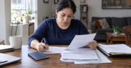 Persona adulta inmigrante revisando formularios y documentos relacionados con una solicitud de residencia permanente en Estados Unidos.